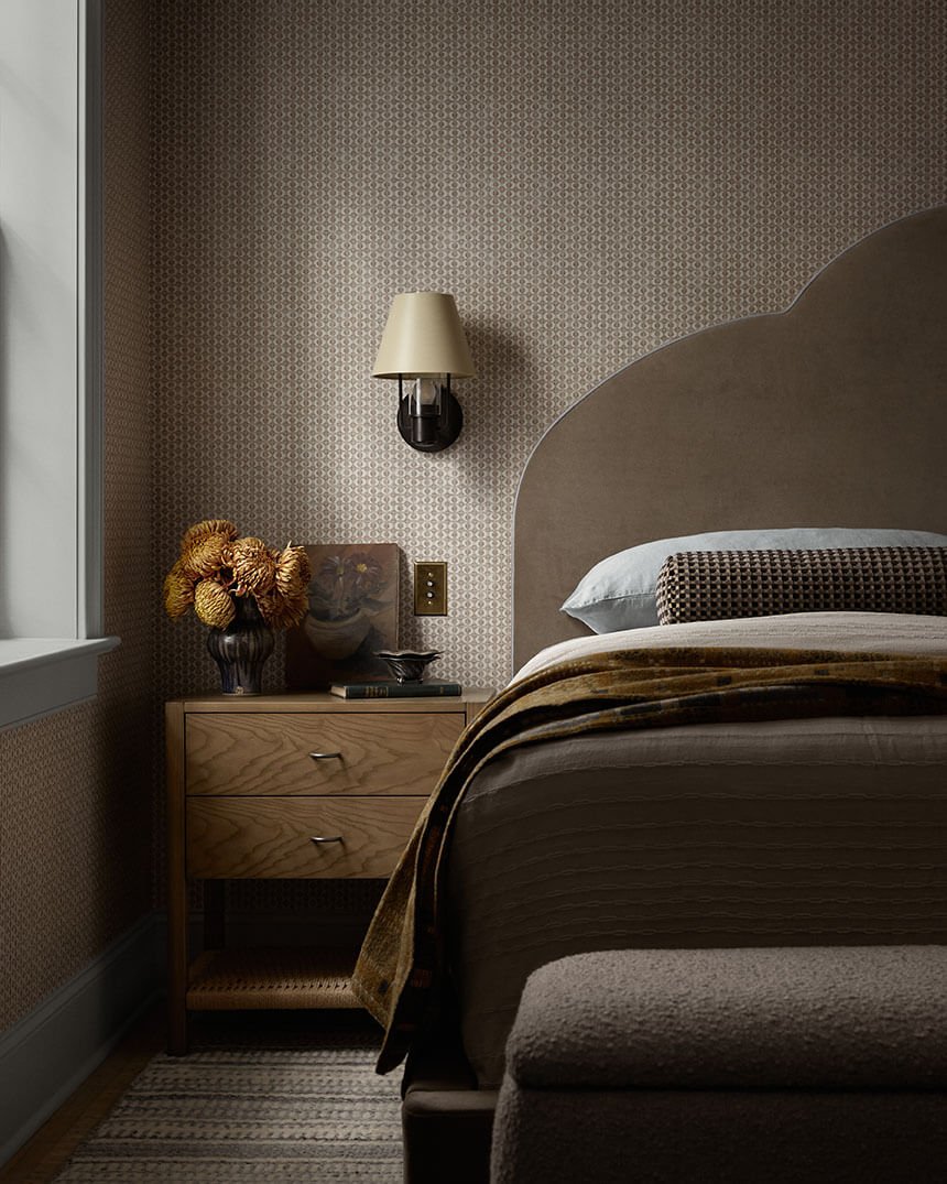 Oak nightstand, brass sconce and upholstered headboard detail in a Philadelphia bedroom by Vestige Home