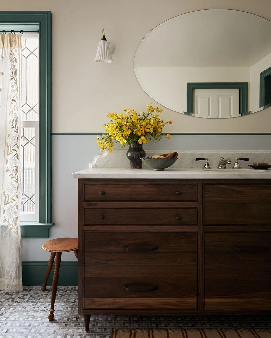 Walnut double vanity with a marble top and oval mirror in a Philadelphia primary bathroom by Vestige Home