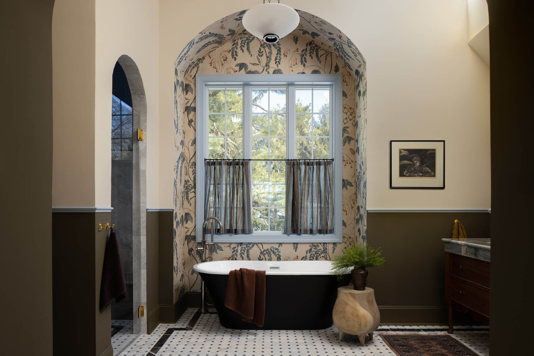 Luxury bathroom in Penn Valley, PA featuring a freestanding soaking tub framed by an arched niche and botanical wallpaper, designed by Vestige Home.