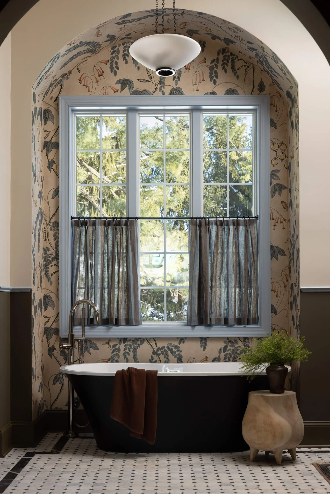 A beautiful, elegant bathroom with floral wallpaper, dark blue soaking tub, custome tile floors, and a plant by Philadelphia interior design firm Vestige Home.