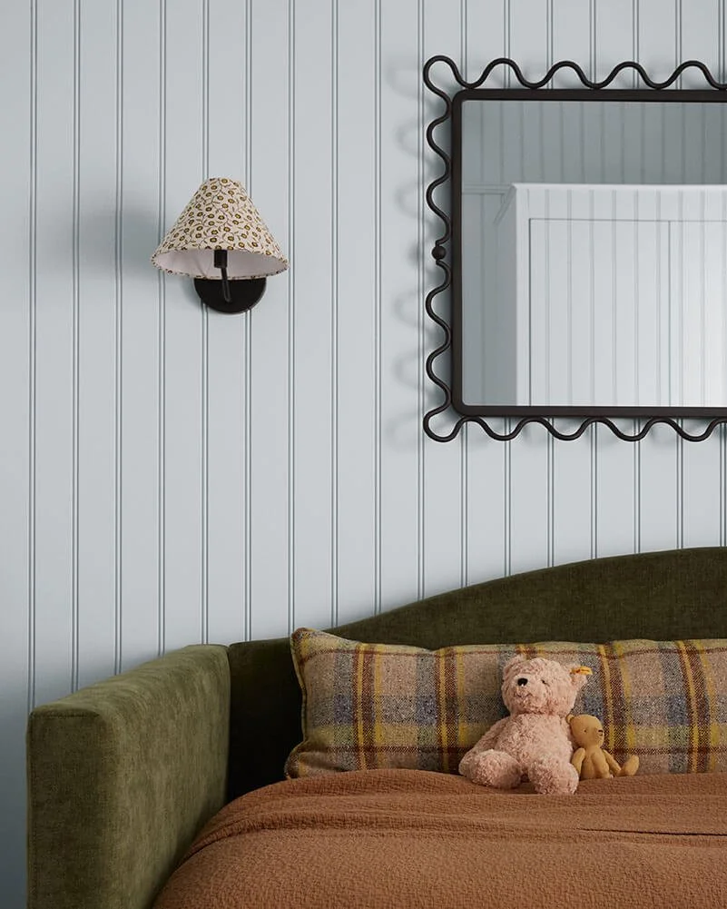 Wavy black mirror, a patterned sconce and green velvet bed in a child's bedroom by Vestige Home Philadelphia