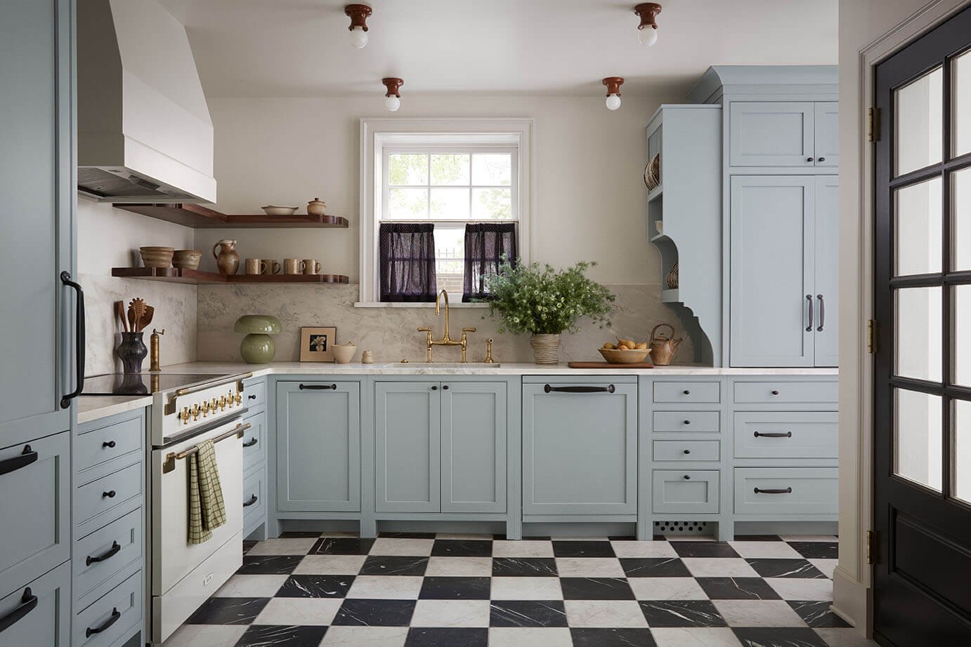 Luxury kitchen design in Philadelphia by Vestige Home with blue cabinetry, brass fixtures and a checkerboard marble floor