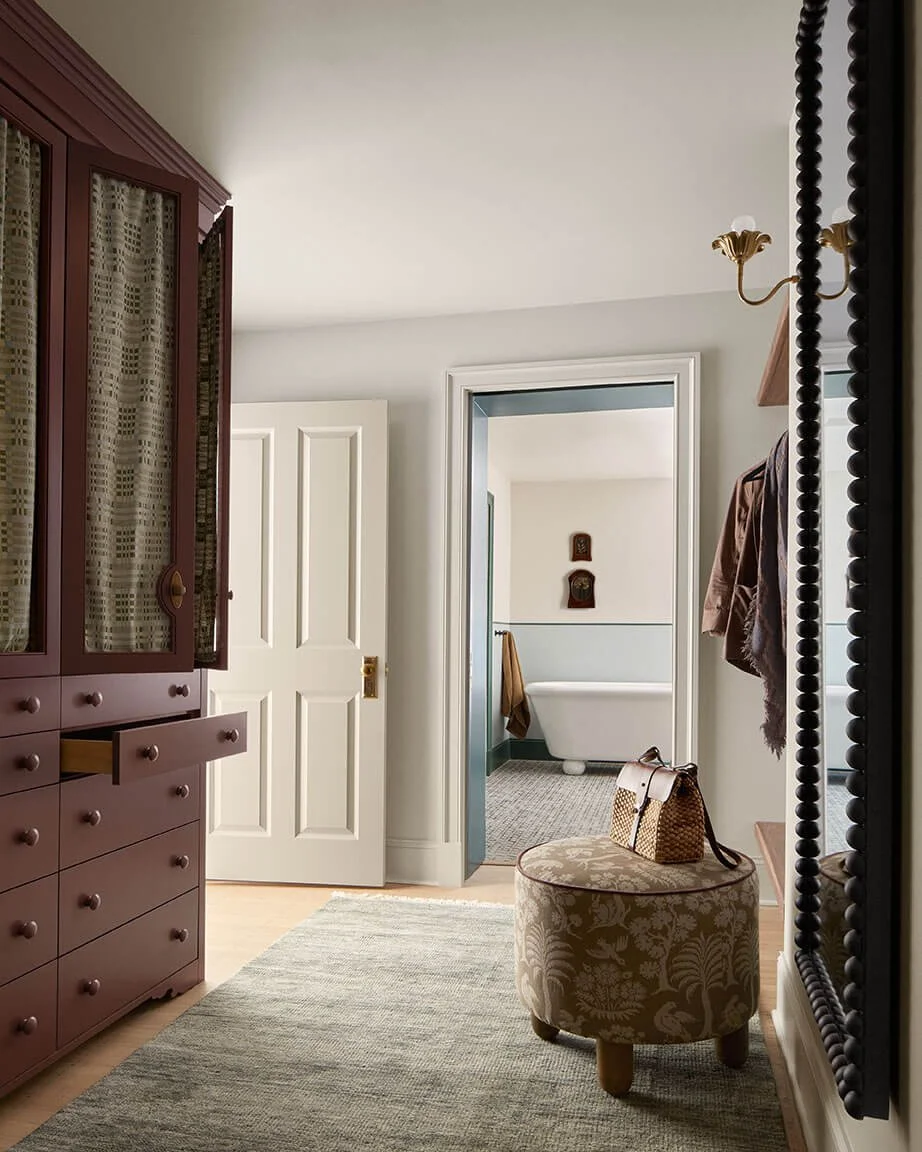 Aubergine armoire and floral ottoman in a Philadelphia primary suite dressing area by Vestige Home