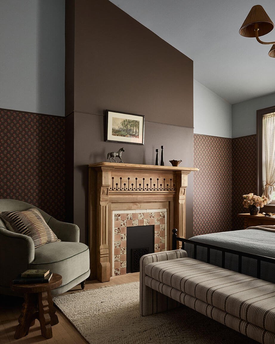 Antique pine mantel with a floral tile surround and green velvet chair in a Vestige Home Philadelphia guest bedroom