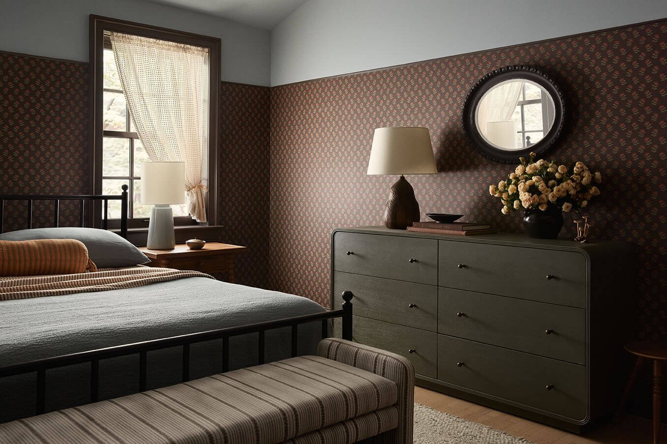 Bedroom with an olive dresser, round mirror and dark floral wallpaper in a Philadelphia home by Vestige Home