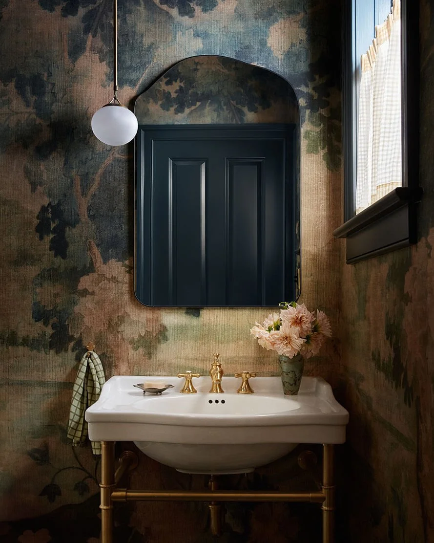 Powder room in a Philadelphia home by Vestige Home with moody floral wallpaper, brass fixtures and a pedestal sink