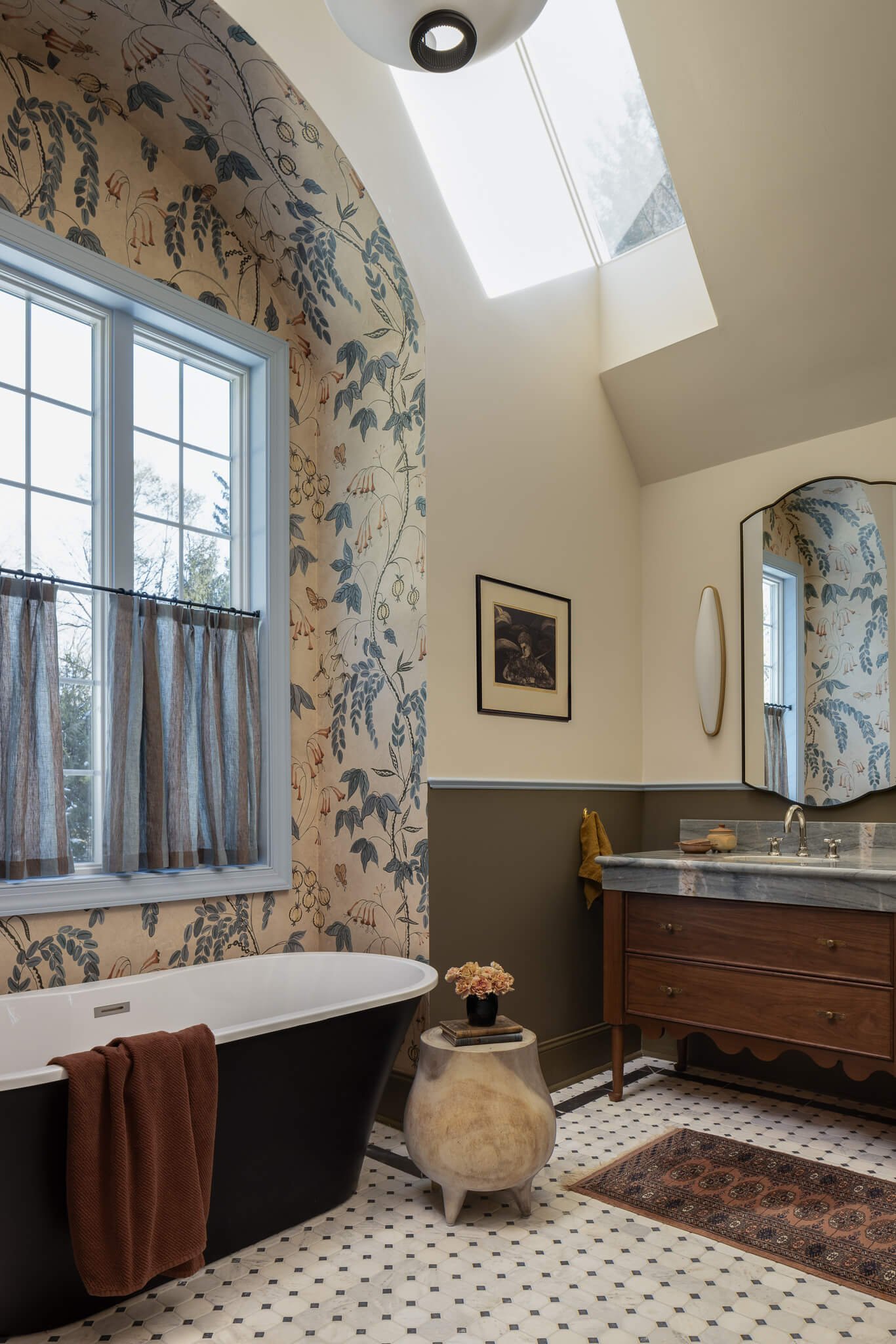 Refined luxury bathroom design in Penn Valley, PA featuring a freestanding tub, skylight, and custom walnut vanity by Vestige Home.