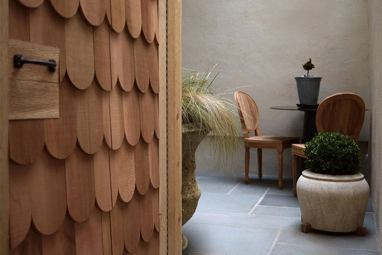 Private courtyard with cedar shake siding and a bluestone patio at a Philadelphia rowhouse by Vestige Home