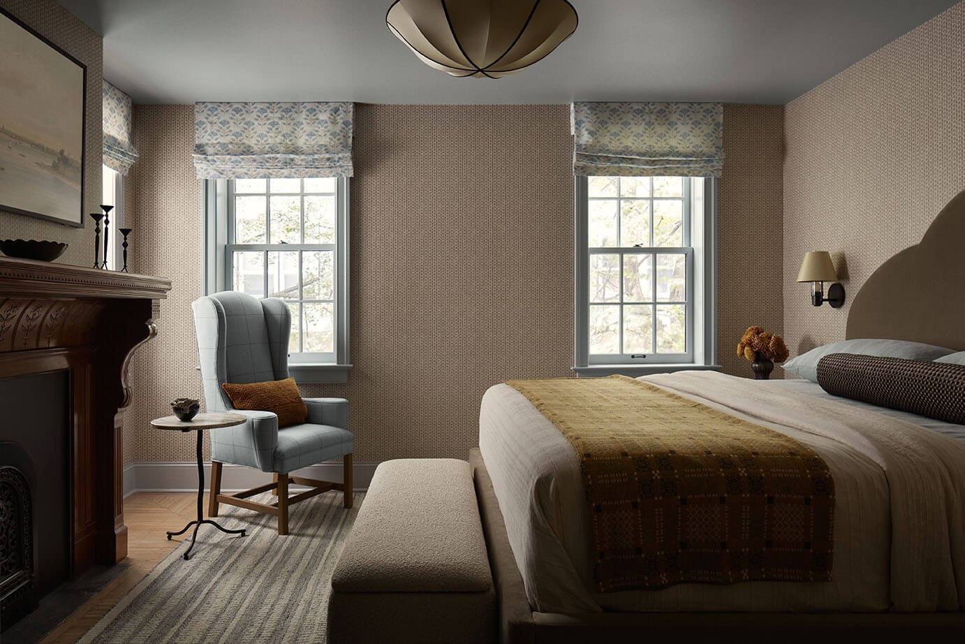 Bedroom in a Philadelphia rowhouse by Vestige Home with an antique carved mantel and block-print wallpaper