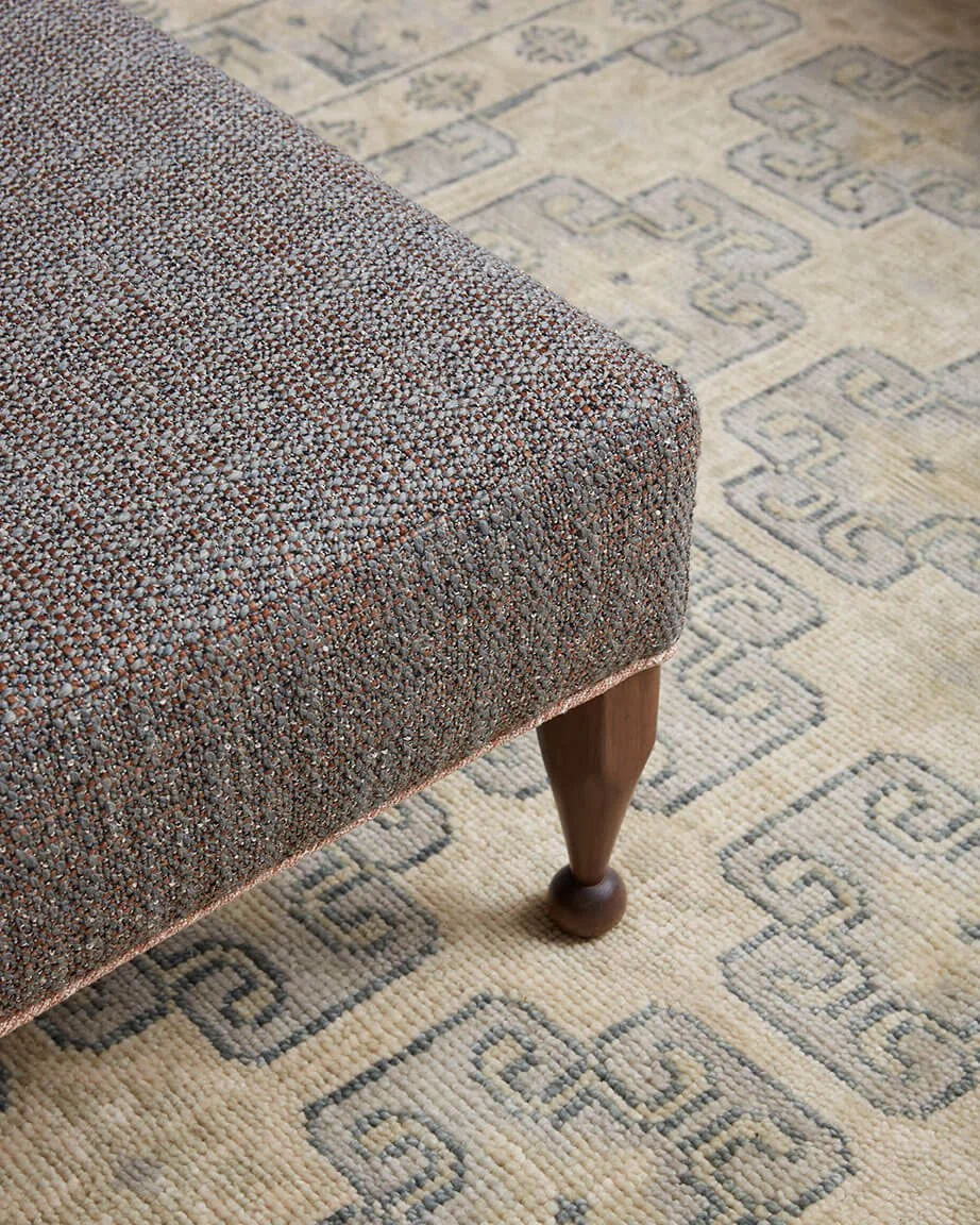 Tweed upholstered ottoman on a patterned area rug, a textile detail from a Vestige Home Philadelphia living room