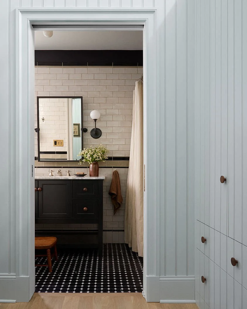 Subway-tiled bathroom with a black vanity and mosaic floor in a Philadelphia home by Vestige Home