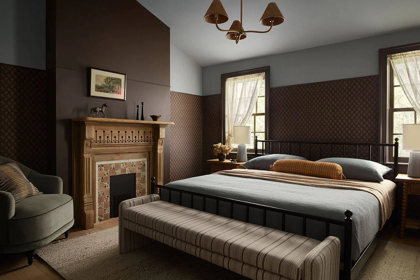Moody bedroom in a Philadelphia home by Vestige Home with dark floral wallpaper and an antique pine mantel