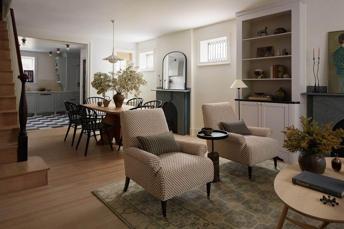 Open-plan luxury living and dining room in a Philadelphia home designed by Vestige Home with checkerboard-patterned armchairs