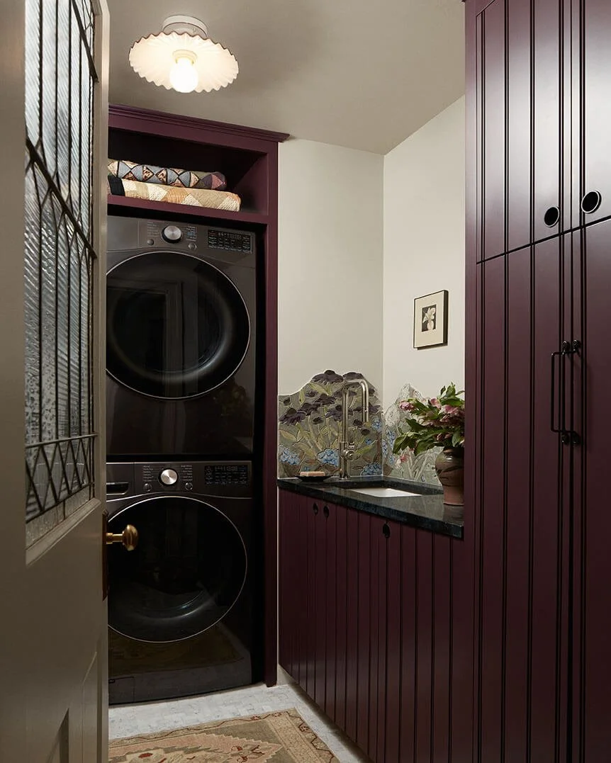 Aubergine laundry room in a Philadelphia home by Vestige Home with a stacked washer-dryer and floral tile backsplash