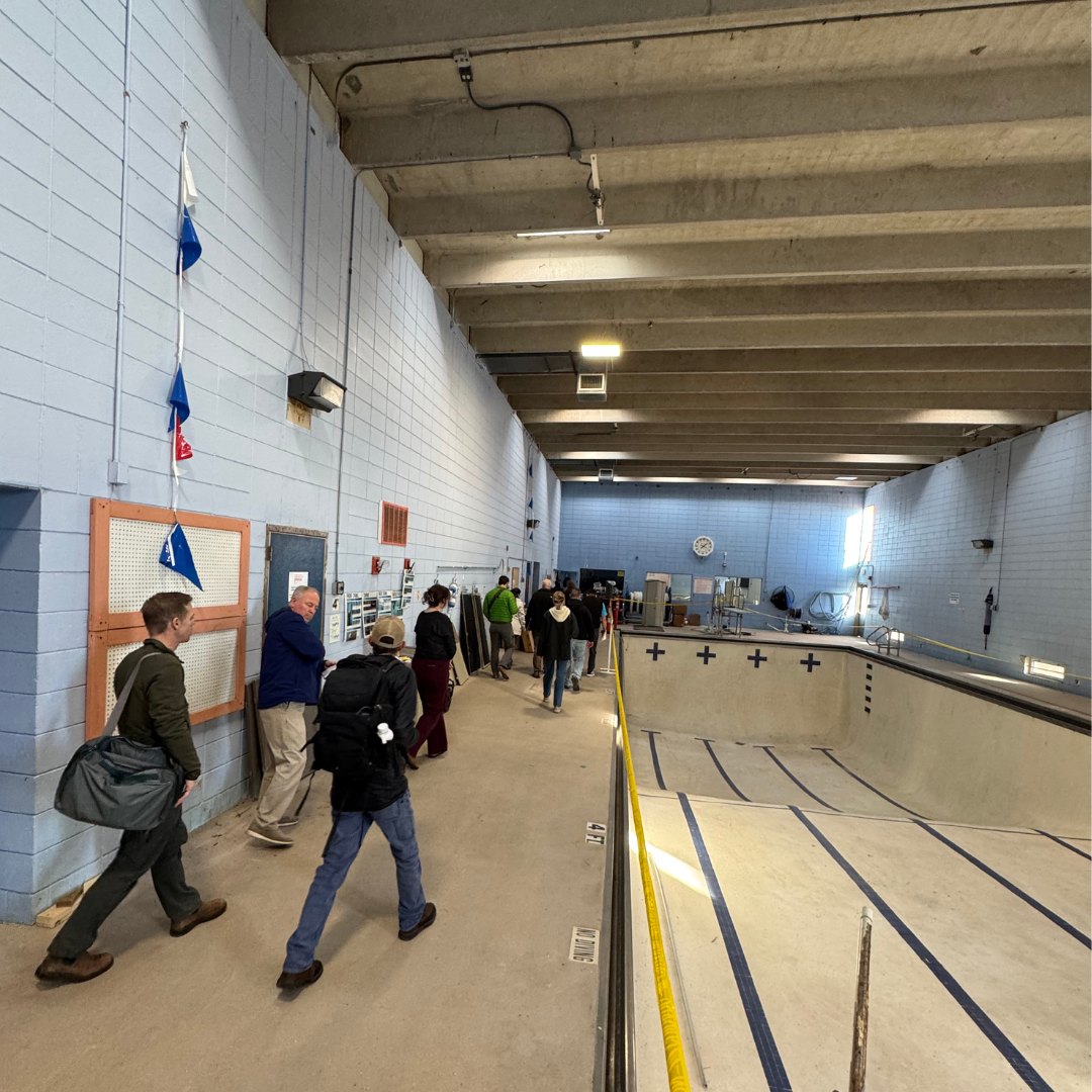 (group of people with workbags walking through the empty pool deck at the YWCA of Asheville)