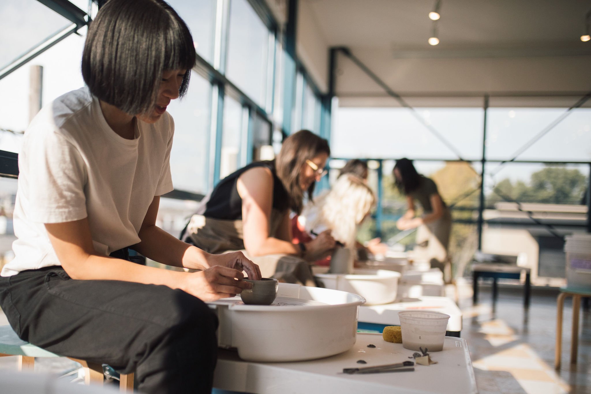 A group of women skillfully crafting pottery together, showcasing their creativity and teamwork.