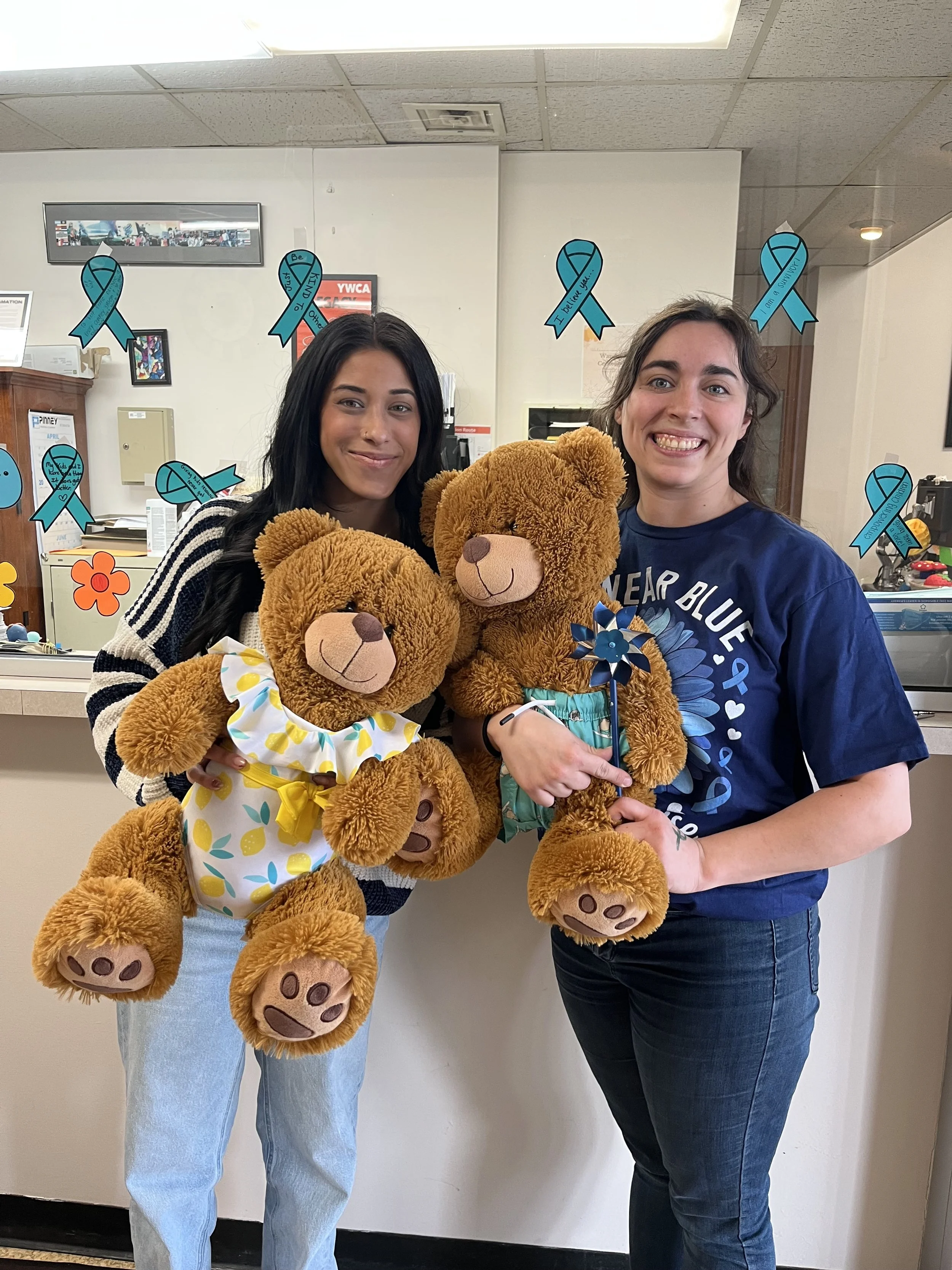 Staff wearing their blue and holding Bo and Brenda Bear in support of Child Abuse Awareness Month
