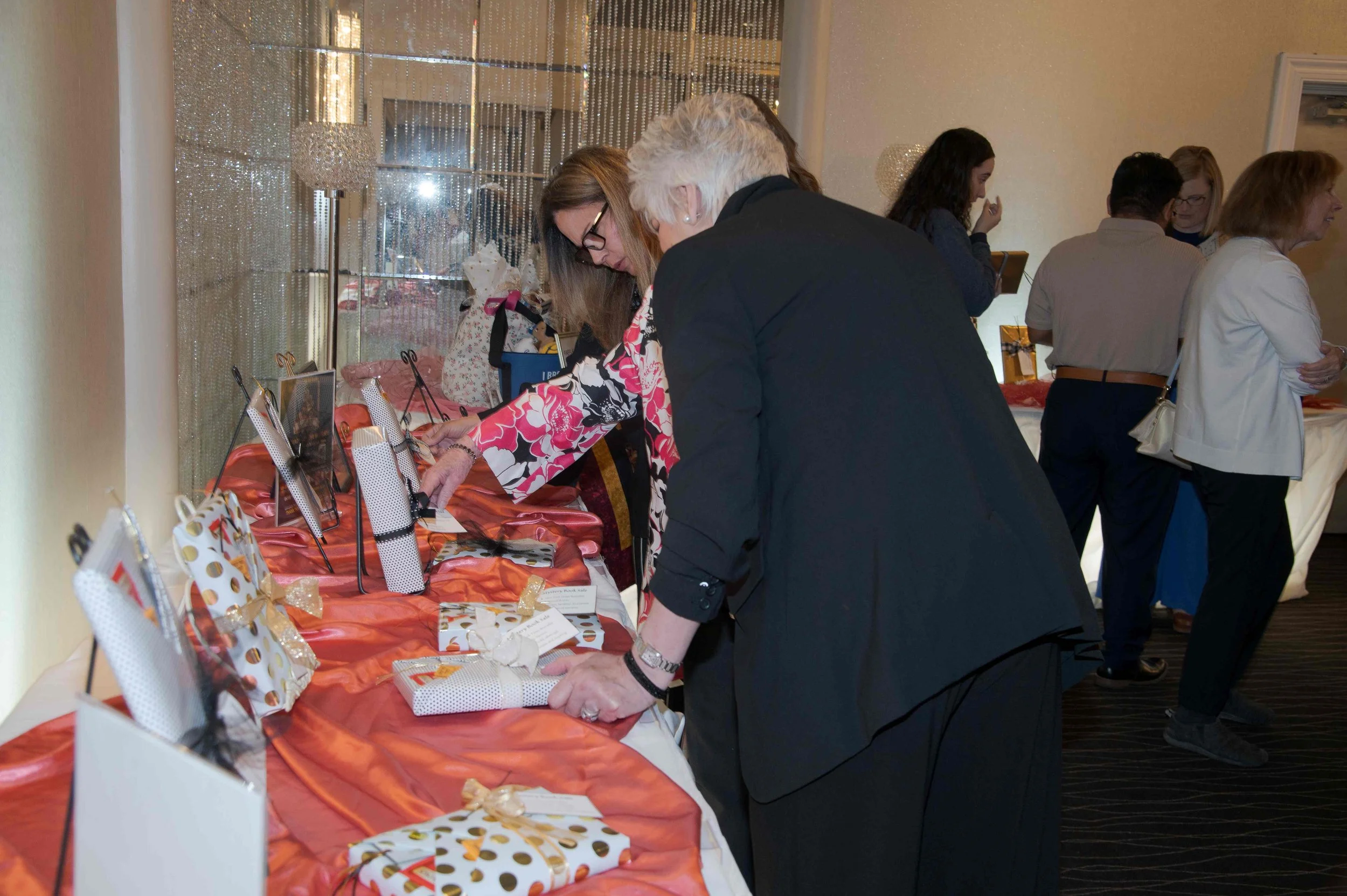People gathered around a table with wrapped gifts at a gift exchange event.