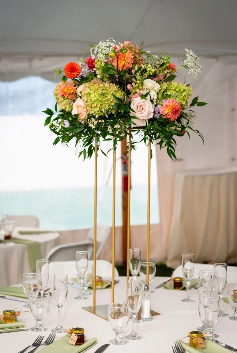 Tall floral centerpiece with various colorful flowers on a banquet table at an event.