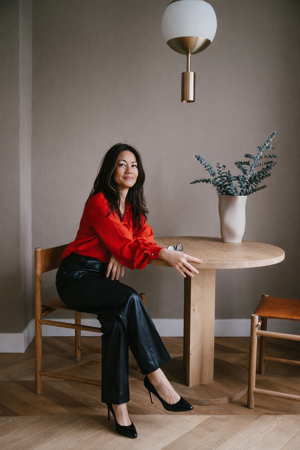 Portret van vrouw in rode blouse aan tafel, representatie van volwassenheid en innerlijke kracht.