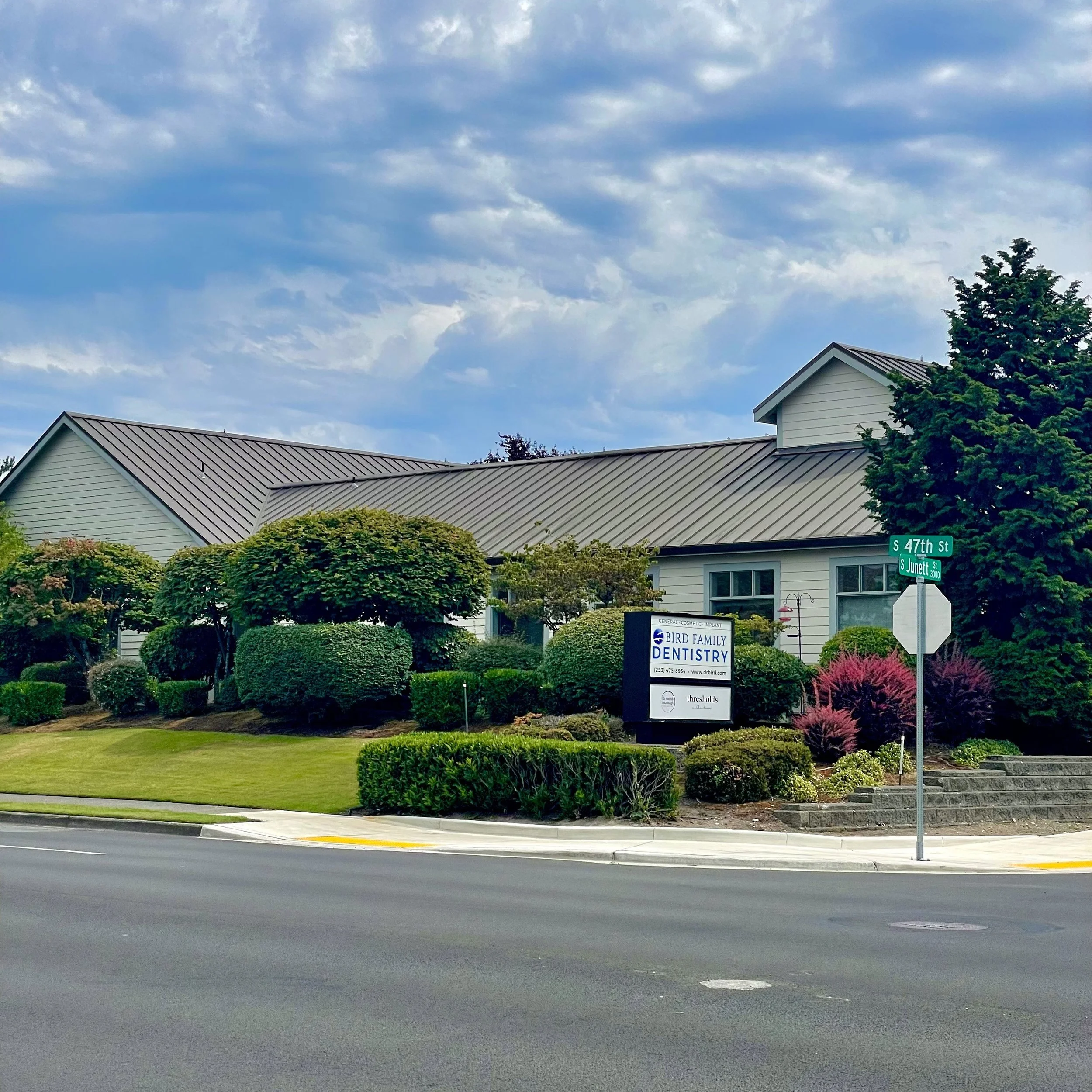Street view of a pelvic floor PT office in Tacoma, Washington along with Bird Family Dentistry, surrounded by calm, welcoming neat landscaped lawn and accessible parking lot.