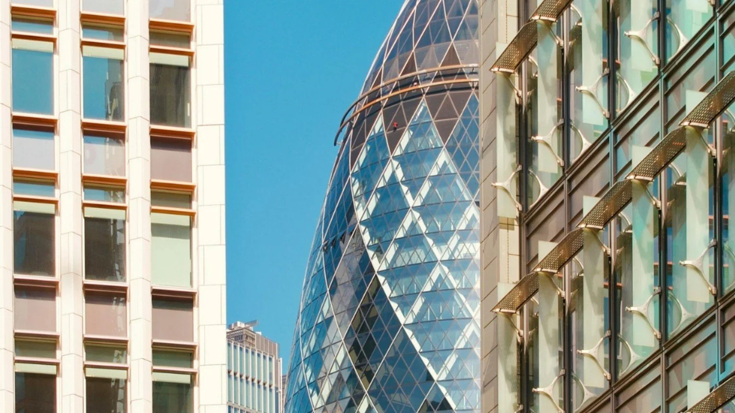 Close-up view of modern glass skyscrapers in a city with blue sky in the background.