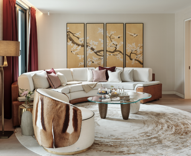 Modern living room with a large sectional sofa, a round glass coffee table, and a traditional Japanese-style folding screen with cherry blossom branches and birds in the background.