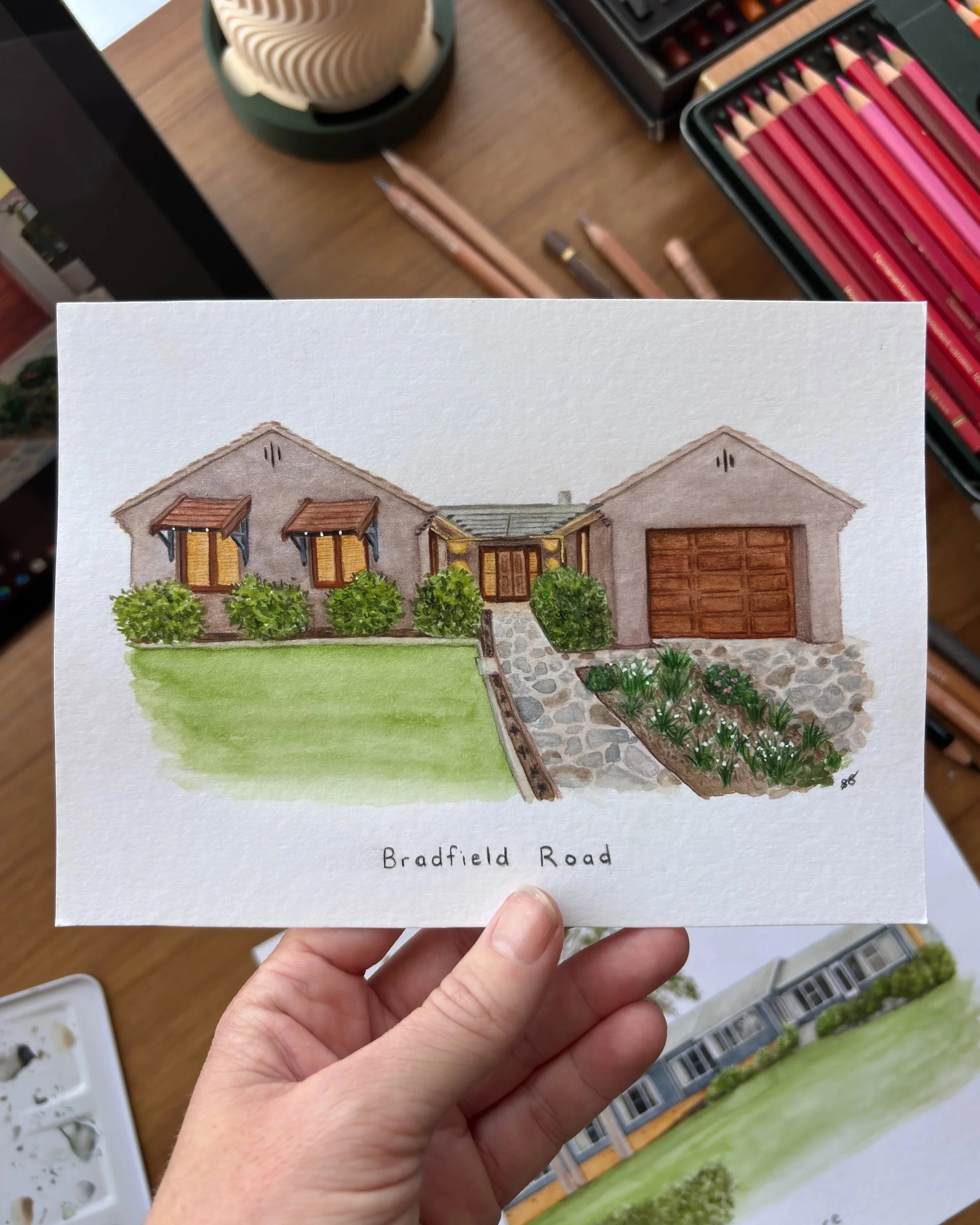 Custom watercolor illustration of a house with bush and flower garden in front, labeled 'Bradfield Road' at the bottom.