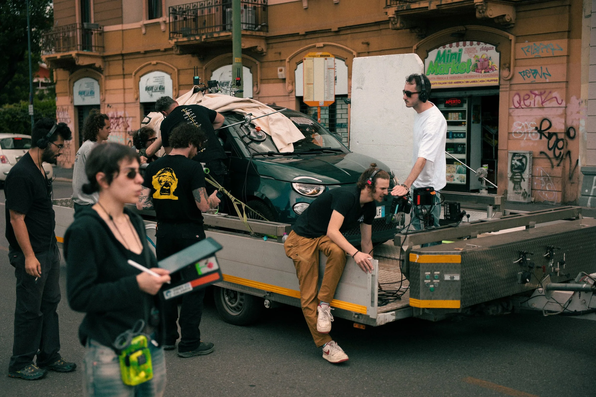 A film or photography studio set with lighting equipment, a white backdrop, and a truck used for production, inside a warehouse or garage.