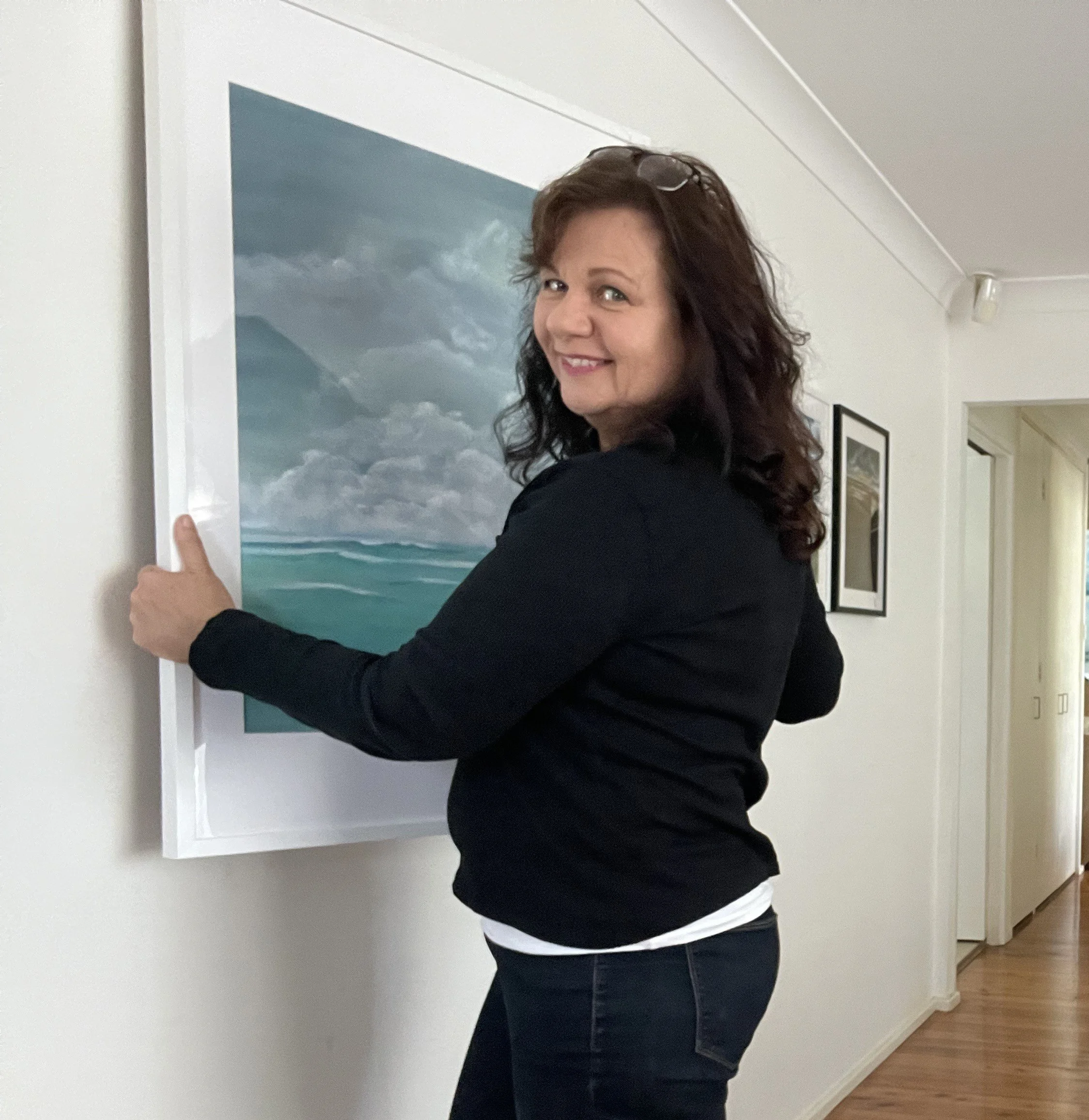 Artist Vivian Kohring hanging an acrylic seascape of the Coral Sea