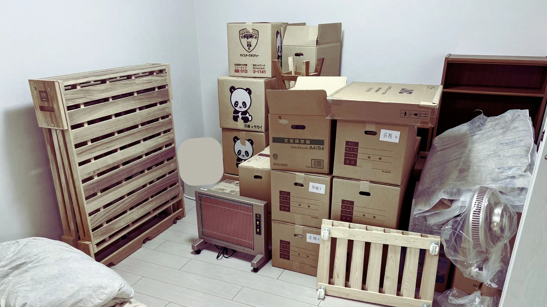 Packed boxes, bed frame and appliances after the move in a white room