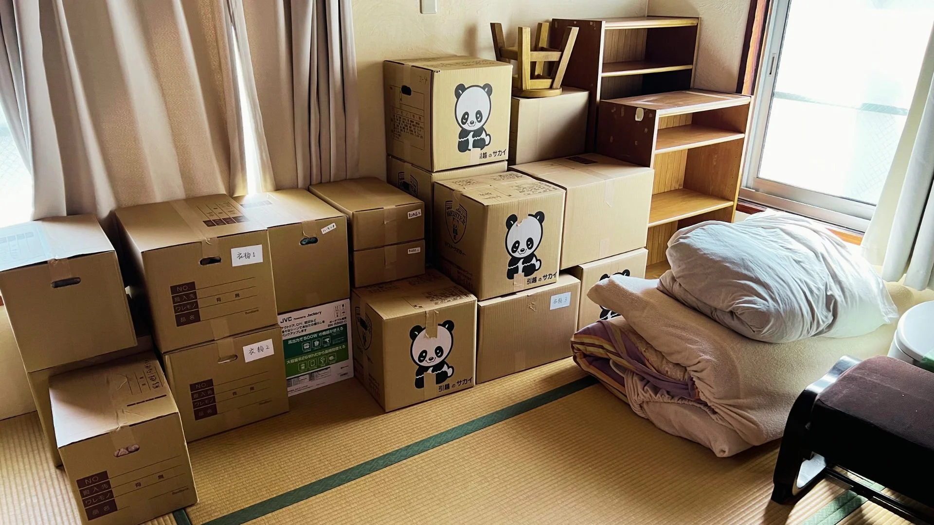 A tatami room with packed boxes, futons and bookshelves