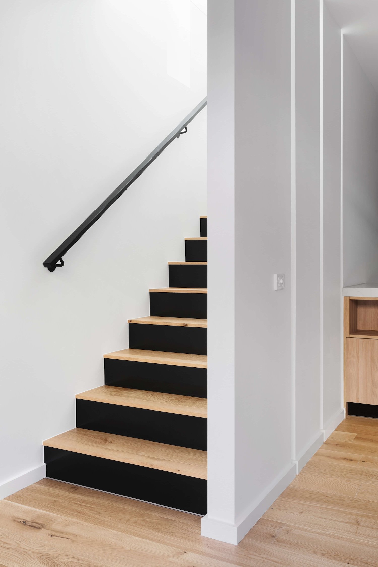 white panelled wall with black and wood stairs