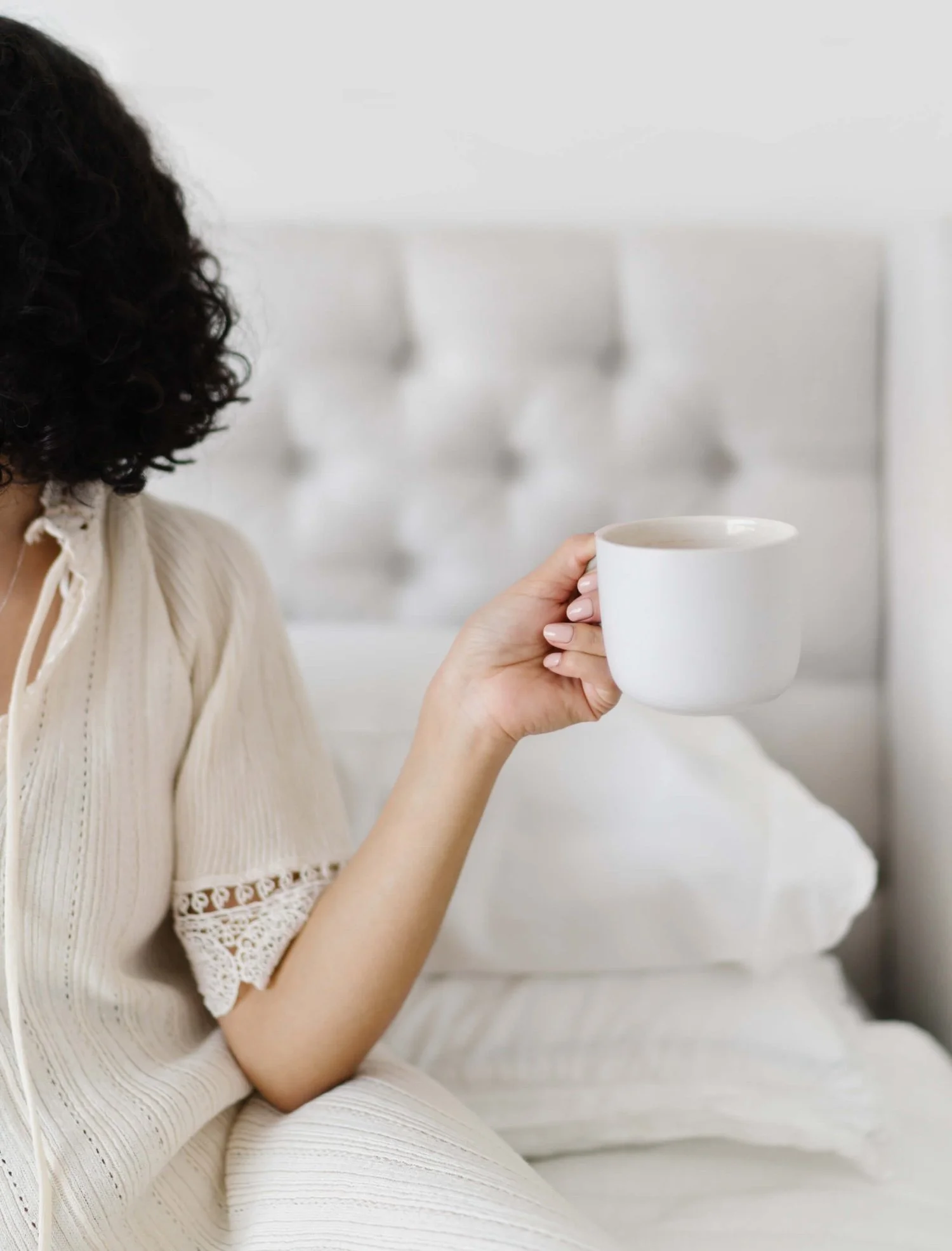 woman on bed holding coffee cup