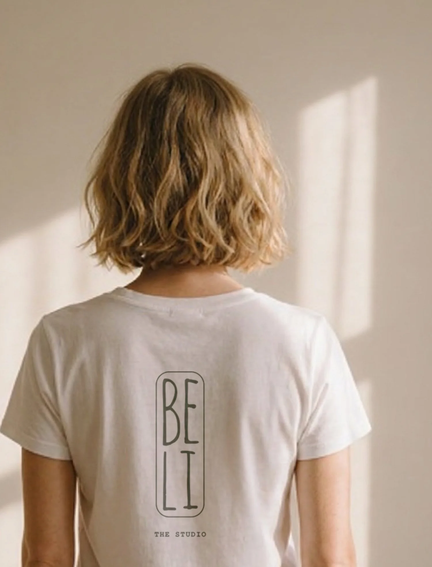 Junge trägt ein weißes T-Shirt mit schwarzen Text 'BE T'.