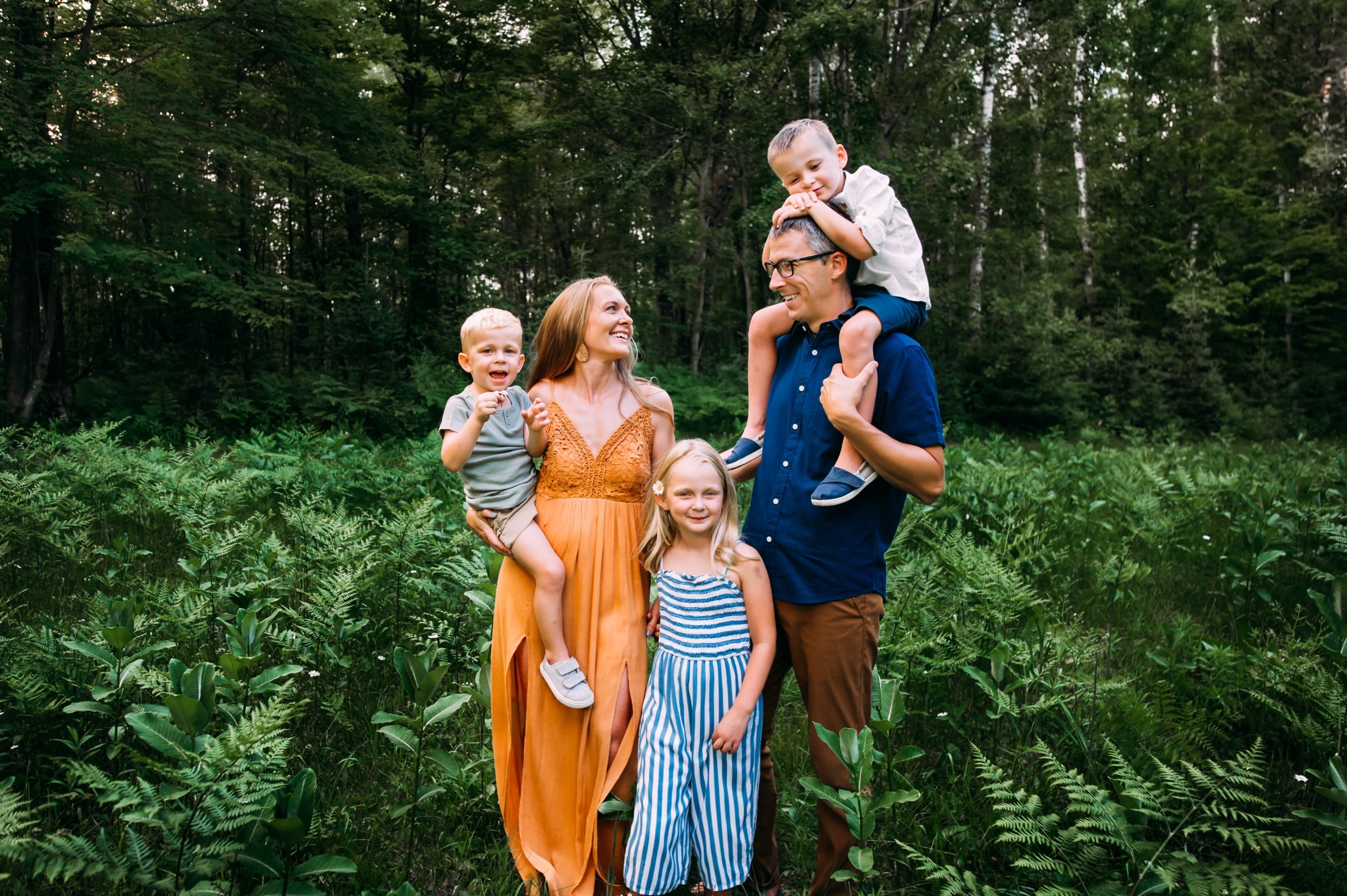 family in green ferns laughs together in their wisconsin family photos