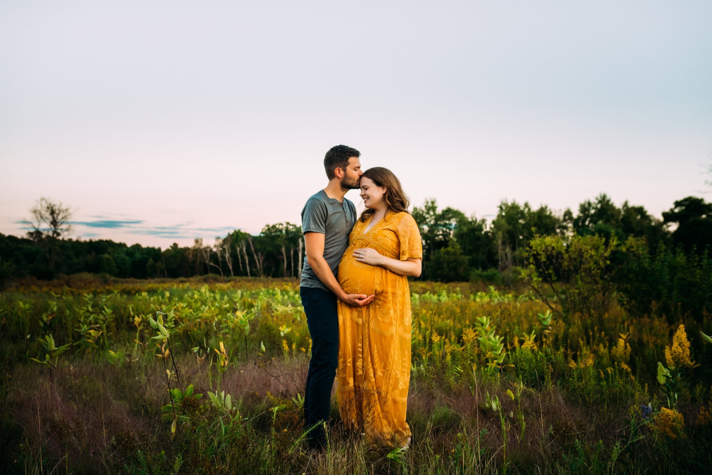 husband embraces pregnant belly in wausau wisconson field