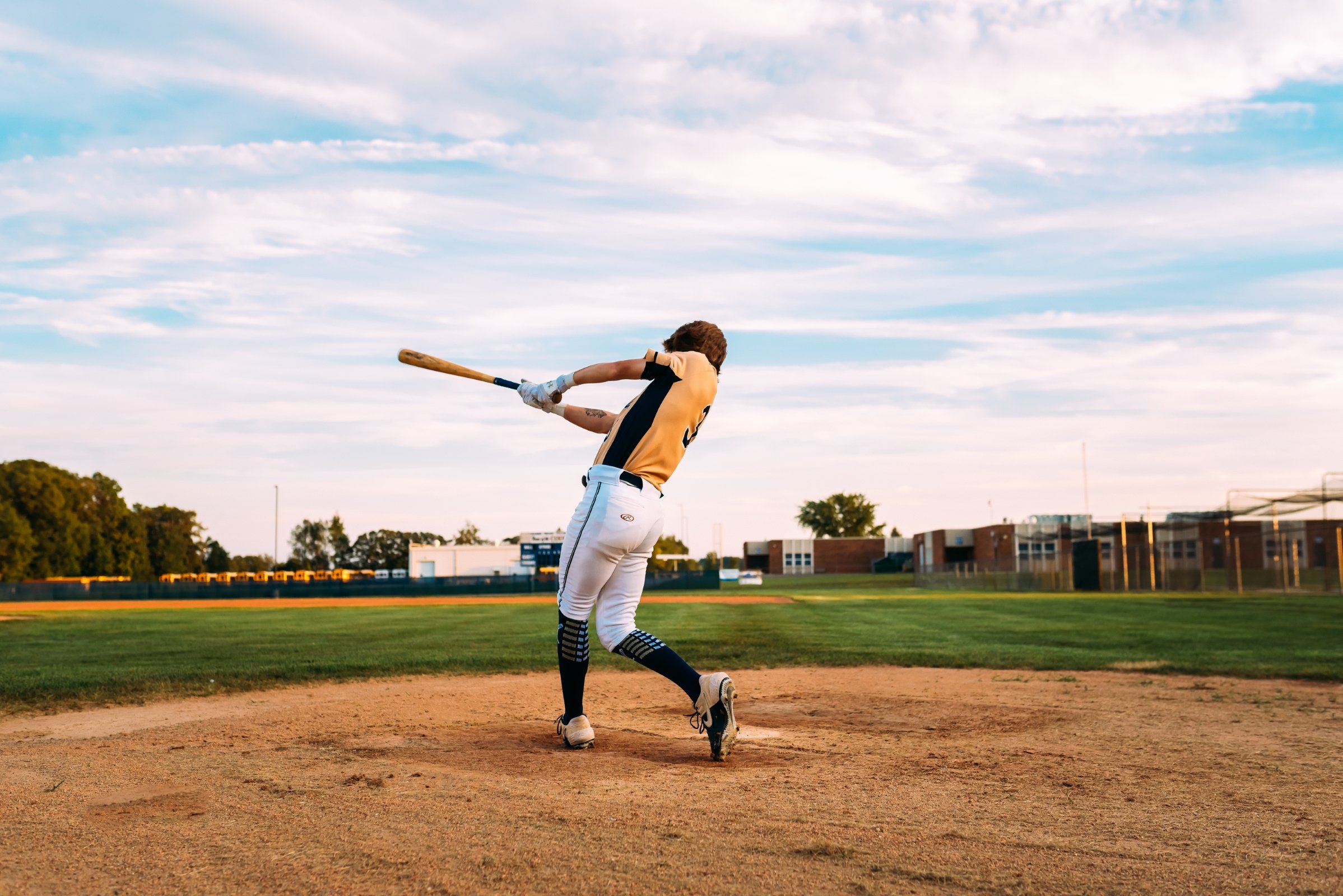 baseball player swings bat in wausau wisconsin for his senior photos