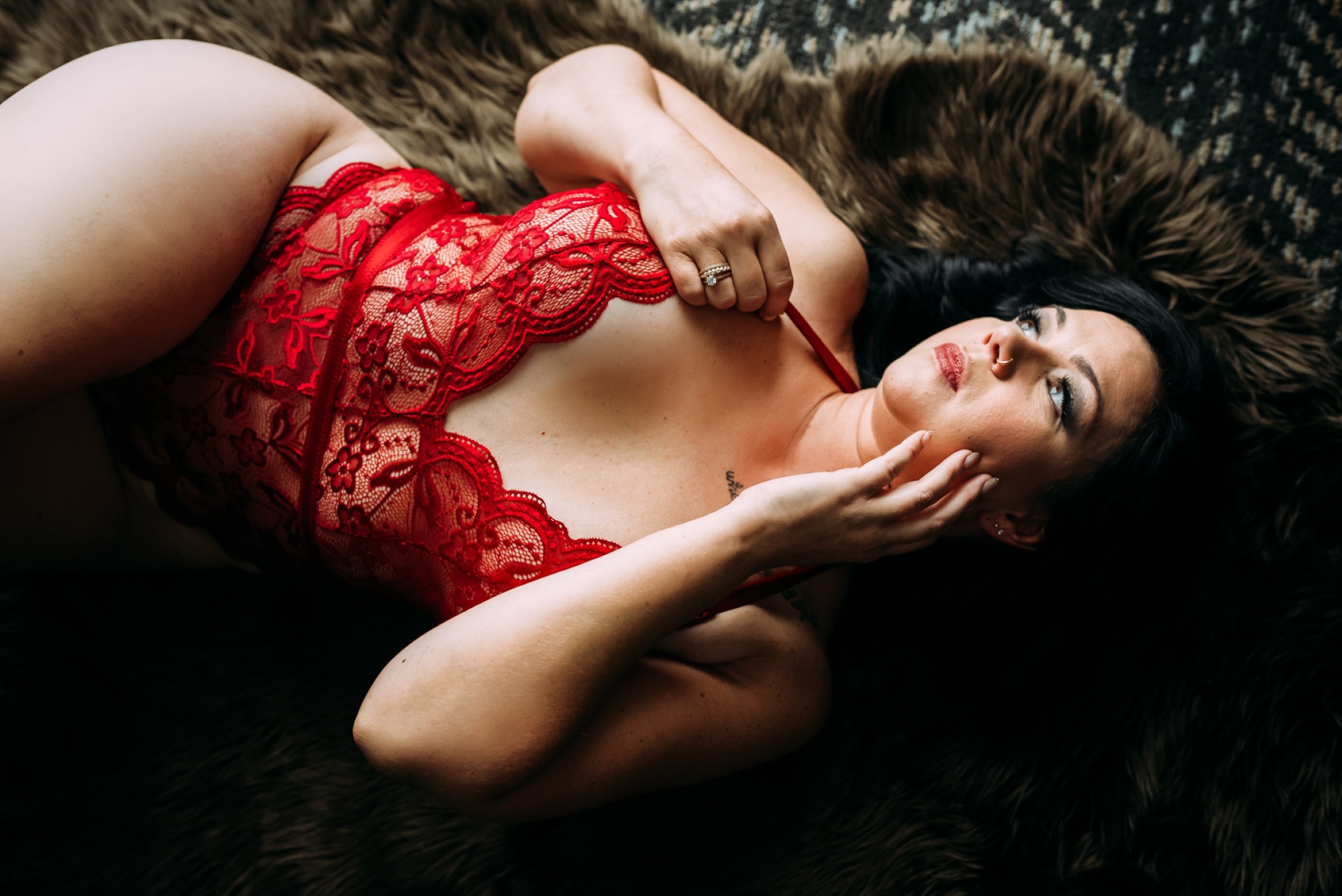 woman in red poses on fur rug for her wausau boudoir session