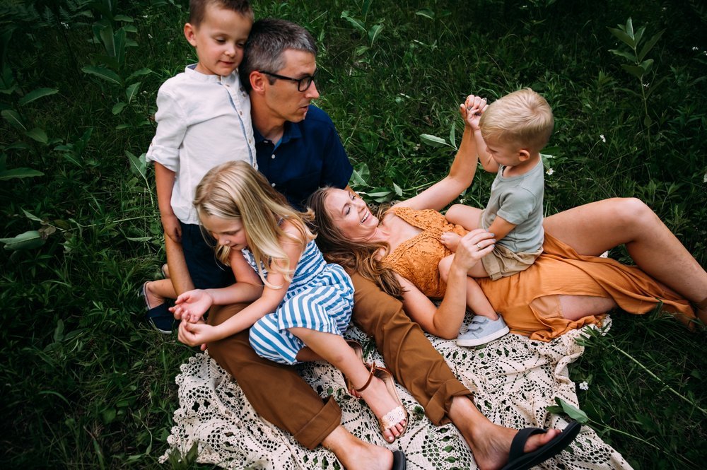 family cuddles on picnic blanket for family photos during summer