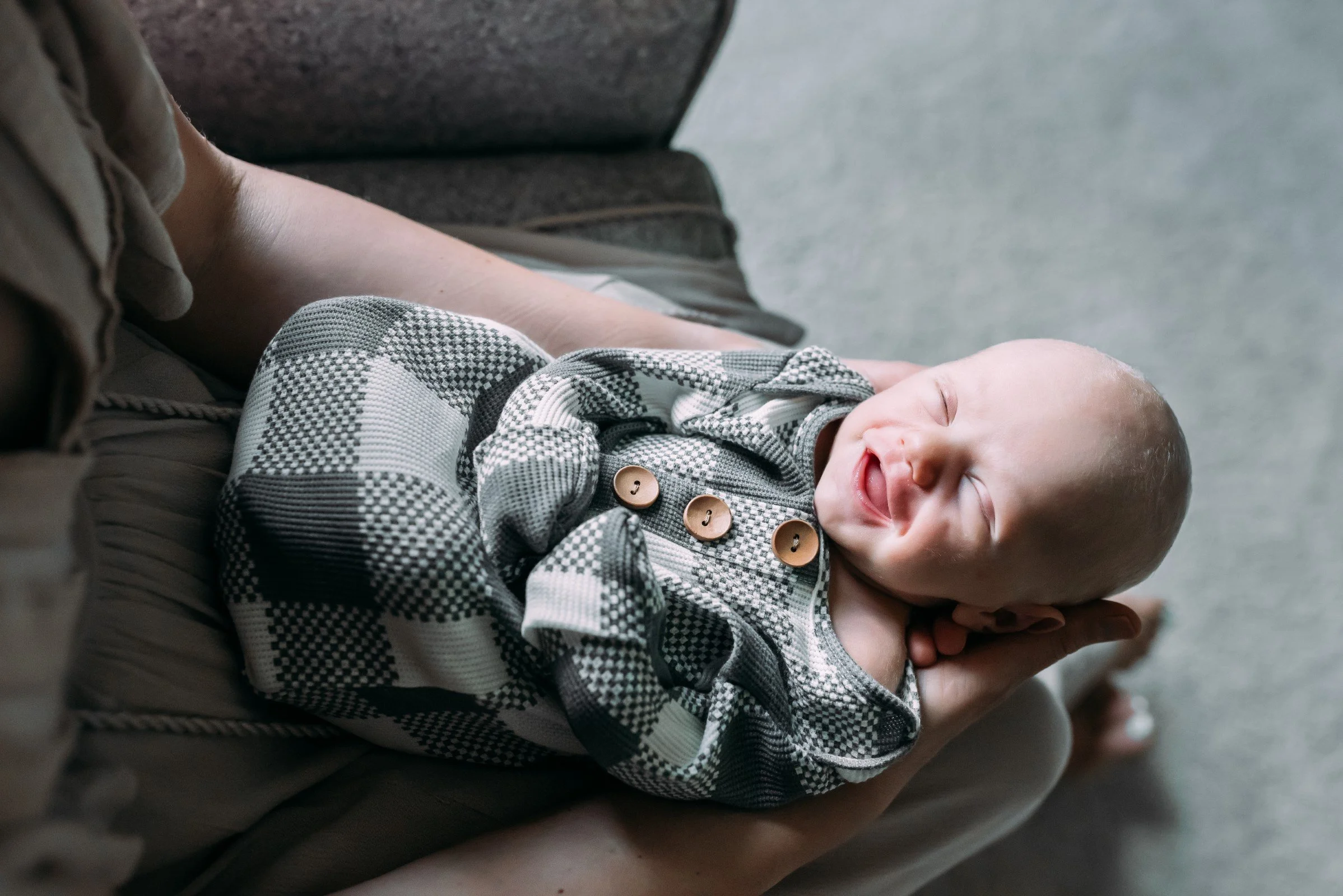 newbonr baby being held in mom's lap smiling during newborn photo session