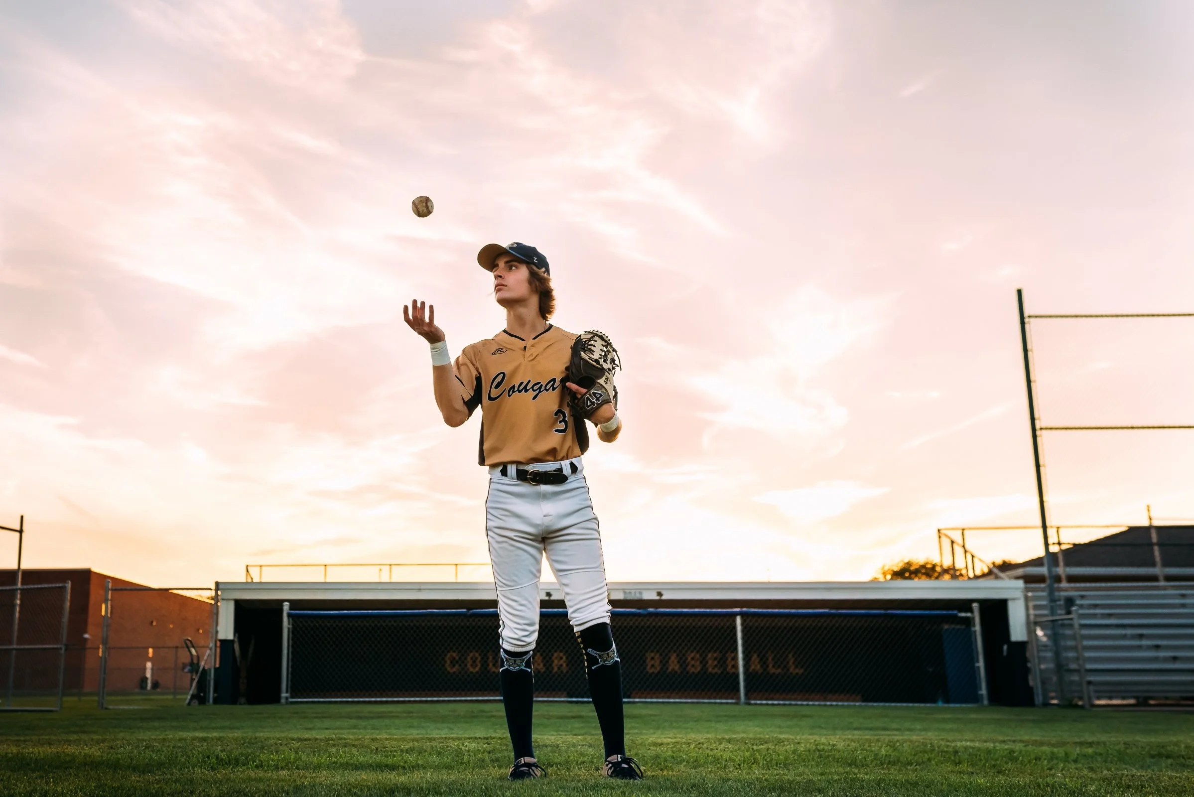senior boy tosses baseball during his uniqu senior photos