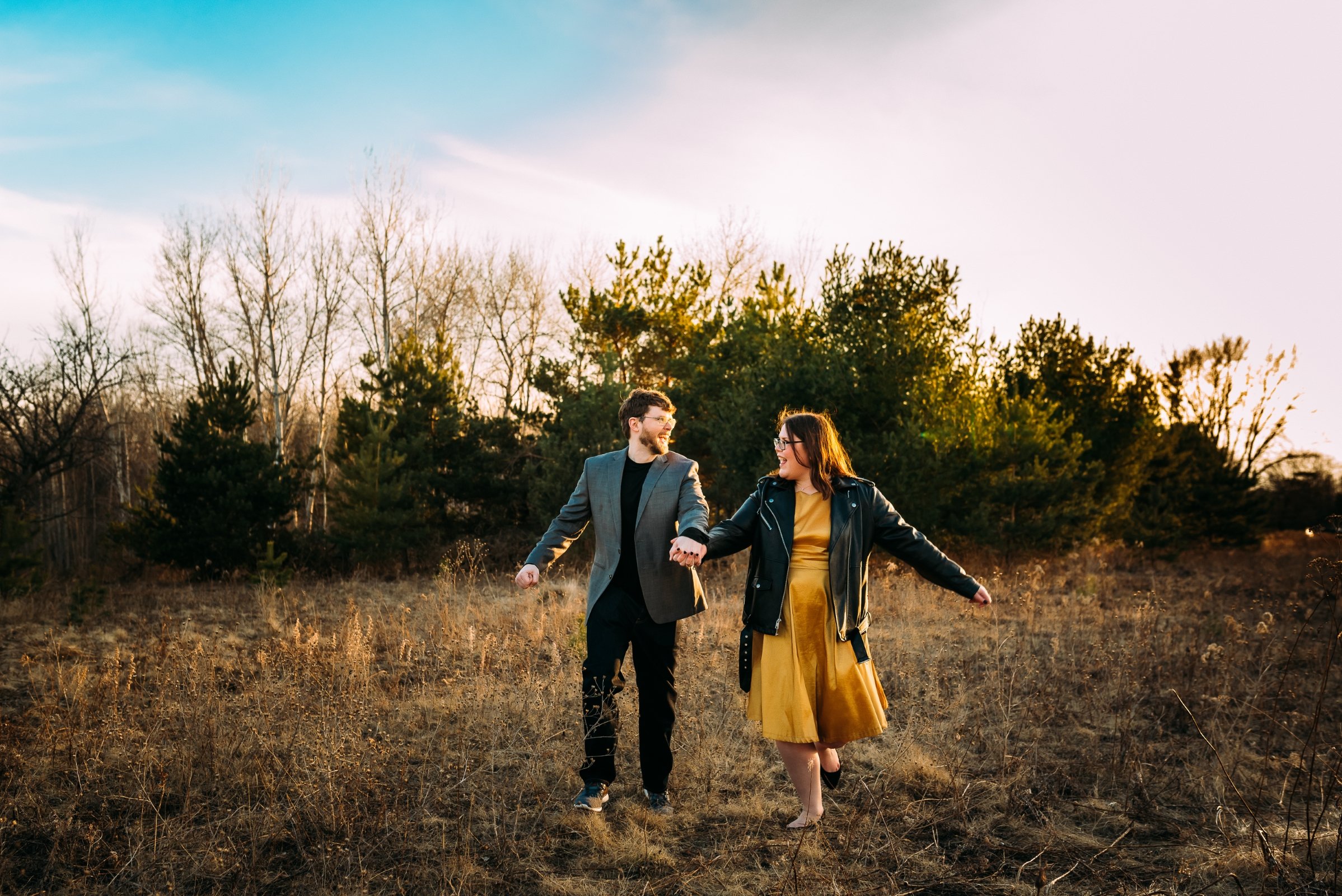 happy couple dance in a wausau field during their engagement session