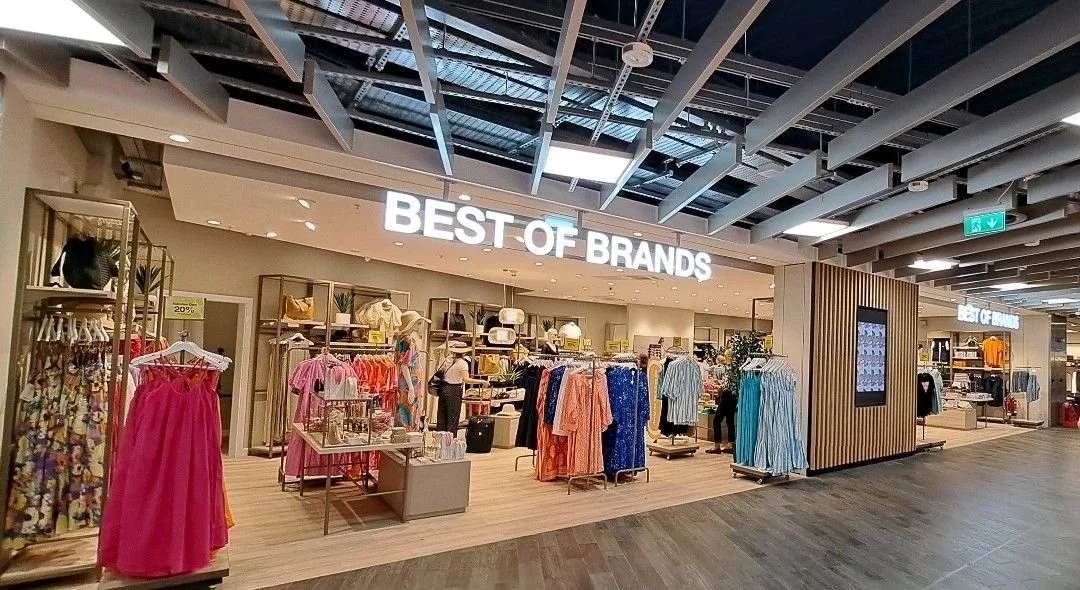 Storefront labeled 'Best of Brands' selling clothing, including dresses, shirts, and accessories, inside a shopping mall.