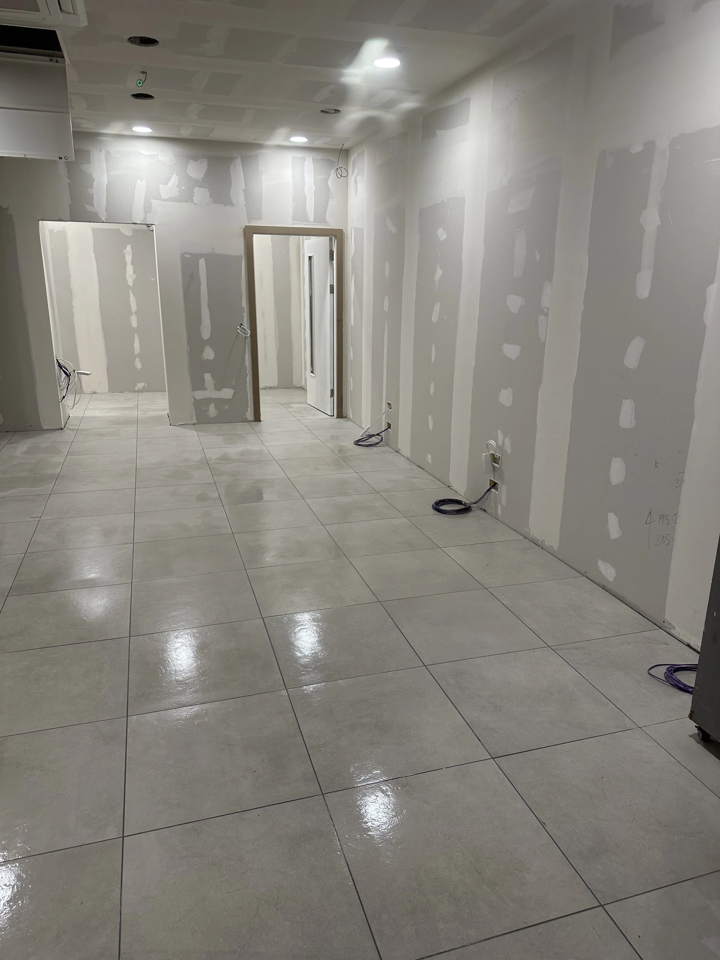 A polished, shiny tiled ceramic floor in a retail store. The tiles are laid in a grid pattern and reflect overhead lighting. The interior appears clean and well-maintained