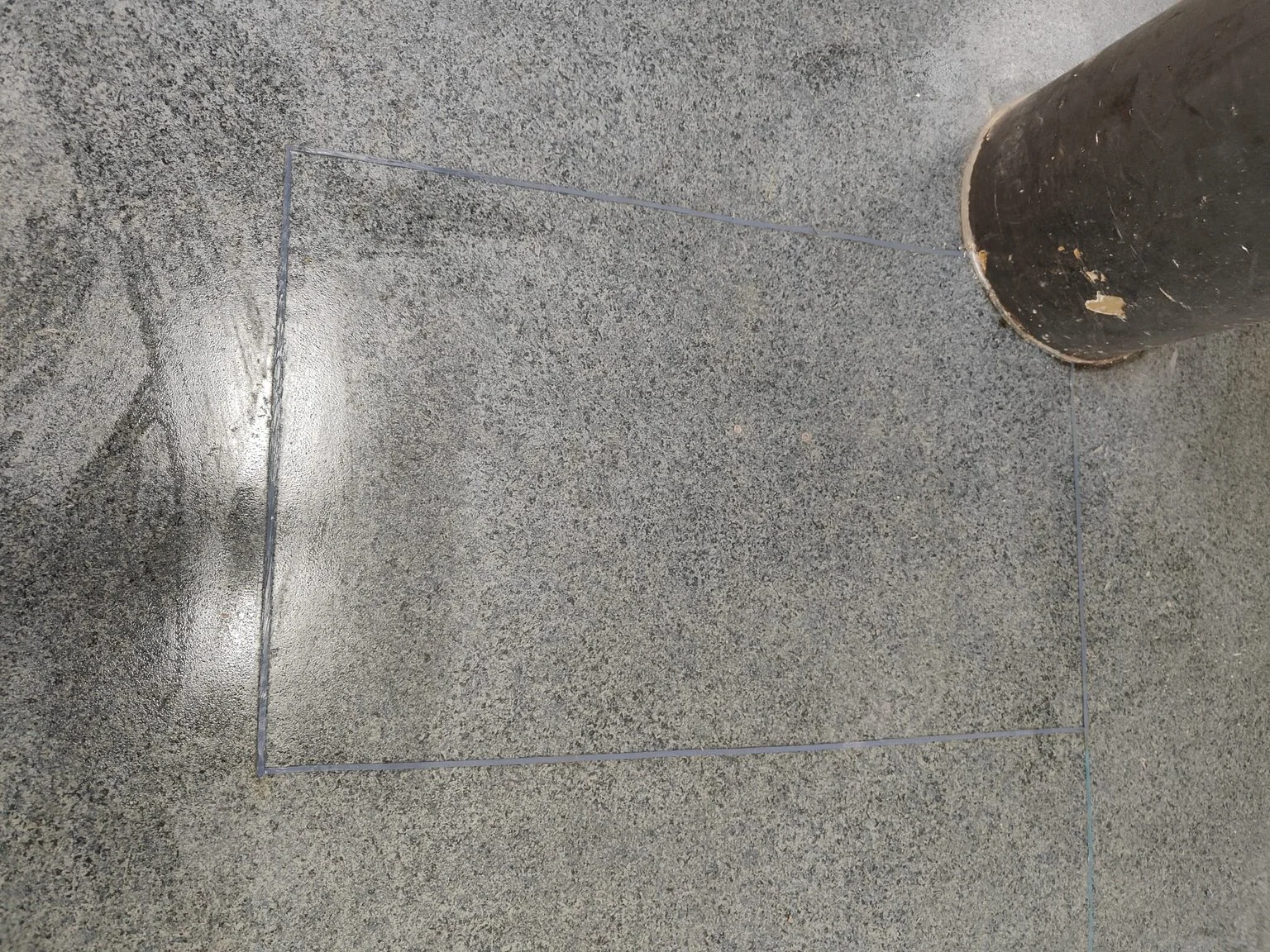 A section of sheet vinyl flooring is visible, featuring a manhole cover on the right side. The repaired area blends seamlessly with the surrounding vinyl. The surface appears smooth and slightly reflective, indicating the new repair