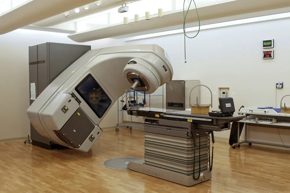 A medical linear accelerator machine in a hospital's radiology room, used for radiation therapy treatment.