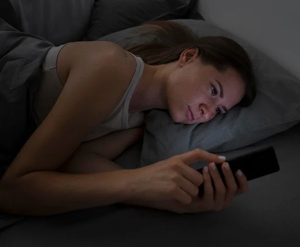 woman asleep in bed on phone