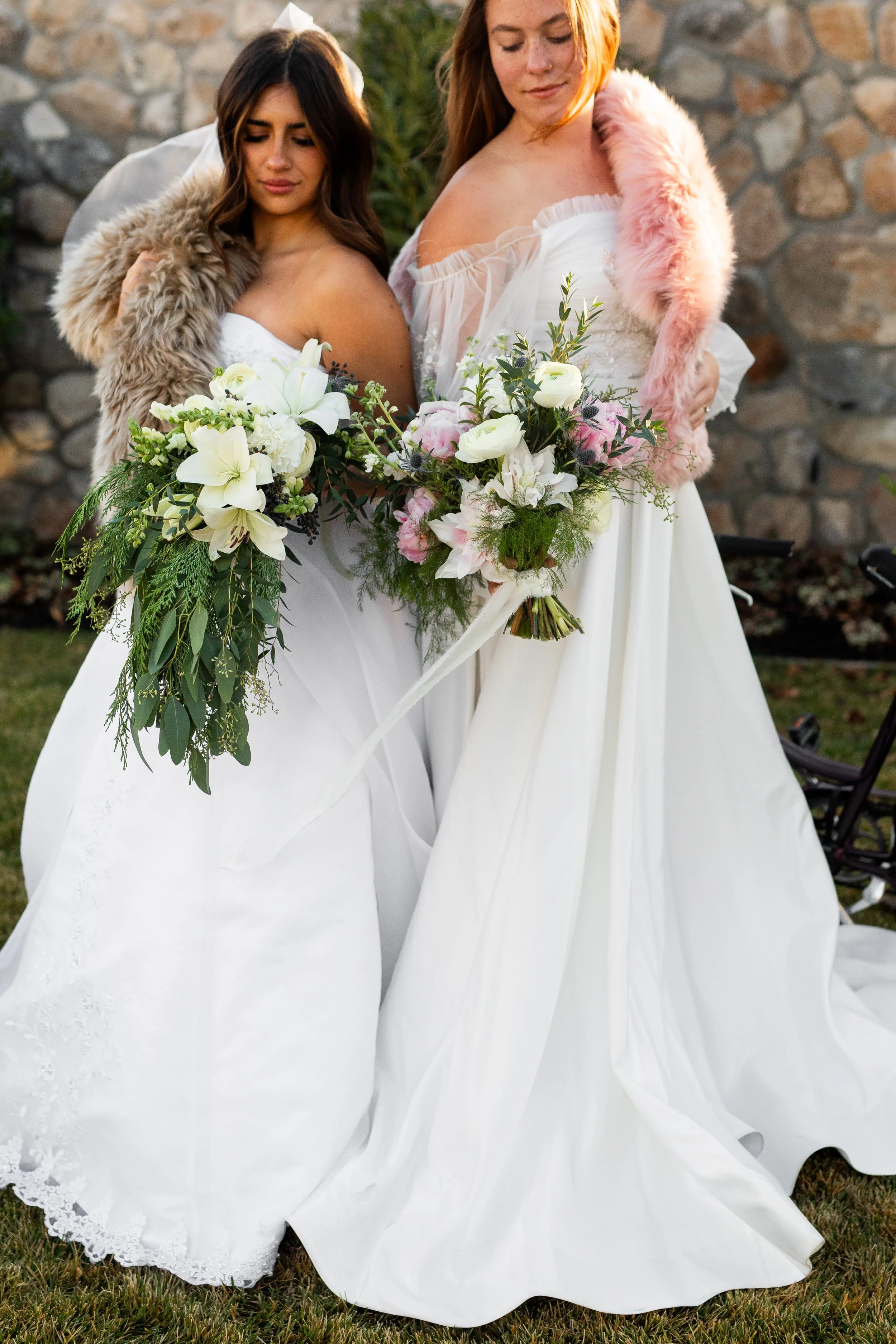 two brides holding bouquets of wedding flowers
