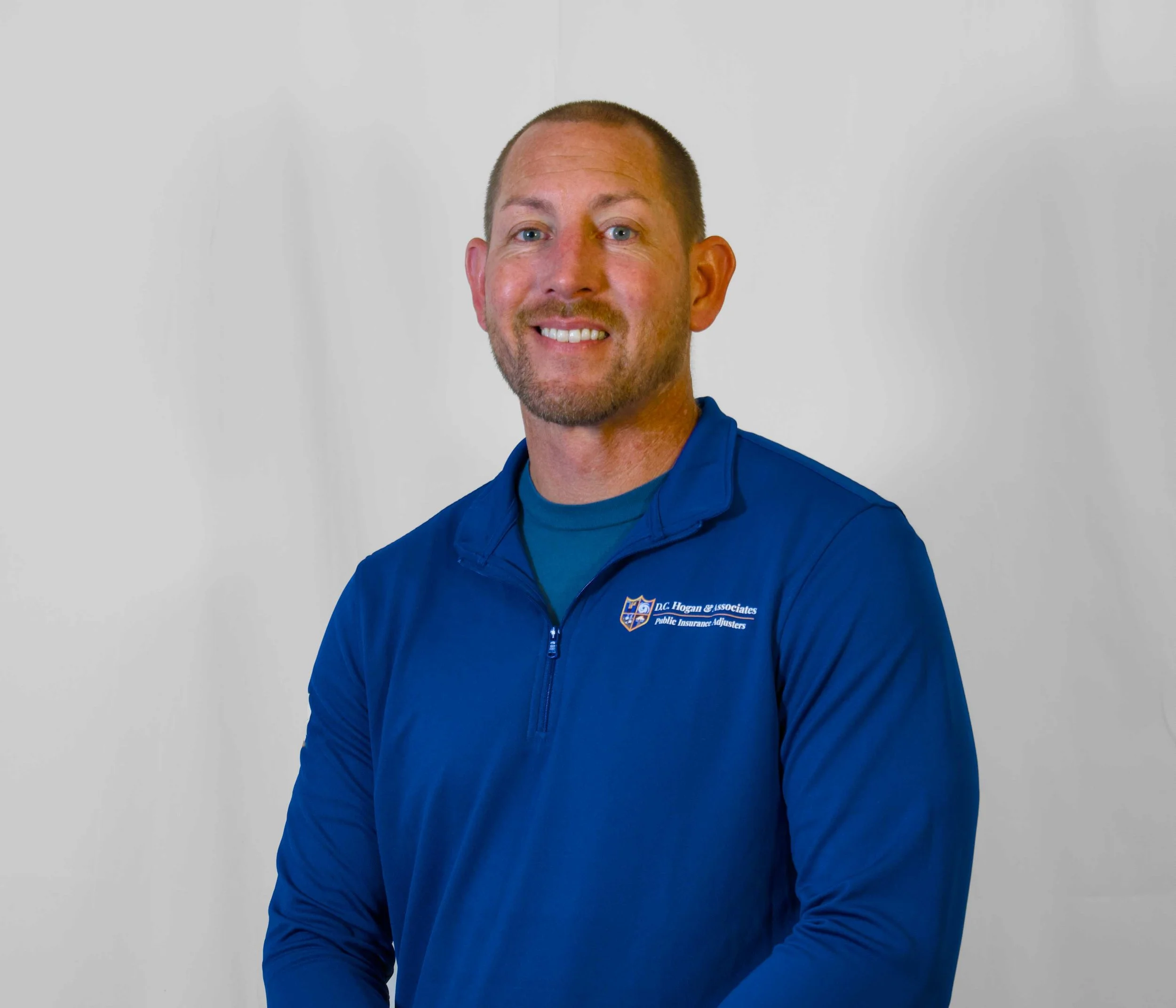 Headshot of Public Adjuster Greg Landry. He is a man wearing a long blue shirt.